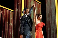 LIONSGATE - AMERICAN IDOL: TV host Caesar Flickerman (Stanley Tucci) introduces Katniss Everdeen (Jennifer Lawrence) to the masses in The Hunger Games.